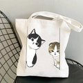 Kawaii white canvas tote bag with cute cartoon cat prints hanging on a black chair - Black White and Tabby Cats
