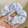 Elastico per capelli blu a pieghe con fiore di camelia crema tenuto in mano - Rosa Blu