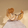 Detailed close-up of golden spiral nautilus bangle resting on a natural stone surface - Nautilus Spiral Unit Open Style