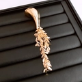 Dettaglio di una spilla geometrica dorata con nappe su un vassoio professionale - Oro - Piccolo