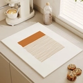 Minimalist cream coffee drying mat with geometric brown patterns on a kitchen counter - Arranged Orange Lines