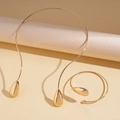 Detail van een minimalistische goudgepolijste druppelkraag en bijpassende open armbandset - Goud