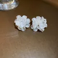 Détail de boucles d'oreilles camélia avec pétales blanc crème sur fond texturé de luxe - Camélia blanc laiteux (7#)