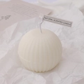 Spherical cream white scented candle with ribbed texture on white textured paper - Sphere
