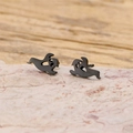 Close-up of black cartoon ghost stud earrings on a textured stone surface - Floating Ghost / Black