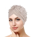 Detailed close-up of beige pleated turban cap featuring white pearls and silver beads - Beige