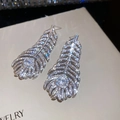 Macro detail of silver feather drop earrings with sparkling cubic zirconia pavé setting - Silver