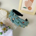 Teal baroque knotted headband with colorful rhinestones on a stylish background - Green