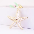 Vista macro de un llavero de estrella de mar en esmalte blanco con borde dorado - Blanco