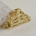 Macro shot of golden metal skeleton hand hair claw clip on a textured beige surface - Alloy Metal / Gold Skeleton Hand (8.5cm)