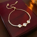 Detailed shot of golden flower bracelet with oval zircons on red wooden jewelry box - Slider Bracelet / Gold