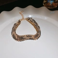 Detailansicht eines goldenen Leoparden-Armbands mit dunklen Strasssteinen und Karabiner - Breites Armband mit Leopardenmuster und Strass / Gold