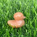 Carved orange natural stone duck figurine placed on green grass for home decoration - Orange Aventurine