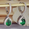 Vista macro di orecchini a goccia in smeraldo a pera con pavé di zirconi scintillanti - Verde