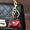 Mini red leather pouch charm with golden hardware on a black quilted handbag - Red