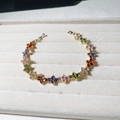 Bracelet trèfle doré avec pierres précieuses colorées sur un plateau de présentation - Or 18K / Doré