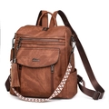 Brown PU leather backpack with tassel detail and extra woven strap on white background - Caramel color