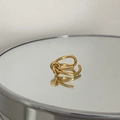 Primer plano de un anillo dorado irregular con nudo metálico y diseño creativo - Diseño de Nudo / Dorado