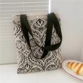 Close-up of beige knit tote bag with dark green floral pattern and snap closure detail - Seed Green