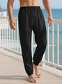 Close-up of black drawstring joggers with a subtle checkered fabric texture on a model - Black