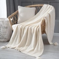 Nordic knitted cream white throw blanket with tassel detail on a wicker chair - Off White