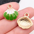 Green and white enamel shell charms in golden finish shown on a fingertip for size - Green Shell 16x17