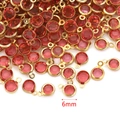 Close-up of 6mm red crystal birthstone charms with golden hoops for DIY jewelry making - Pink