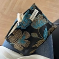 Black canvas makeup bag with blue floral embroidery and a branded white logo label - Plum Blossom Shiny Black Blue