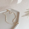 Dettaglio collana di perle d'acqua dolce con chiusura dorata su vassoio minimalista - Sfera dorata Perla di riso fine