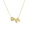 Macro view of gold heart and 'M' pendant necklace with micro-pave white zirconia - Letter M