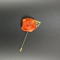 Close-up of orange satin rose lapel pin with golden metal leaf and long needle design - Orange