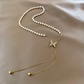 Détail du pendentif papillon doré avec perles sur un luxueux tissu en soie couleur champagne - X880 Or - Style Long de Perle Papillon