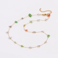 Dettaglio di pietre colorate irregolari su una delicata collana in acciaio inox dorato - Collana