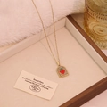 Elegant gold arch necklace featuring a red heart pendant in a vintage jewelry box - White
