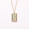 Gold plated The Moon tarot card necklace featuring green enamel, crystals, and moon stars - Moon