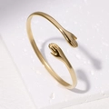Bracciale rigido aperto in acciaio al titanio dorato con design a mani che si abbracciano - Oro