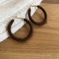 Detailed view of dark brown flocked hoop earrings on a warm wooden surface - Dark Brown