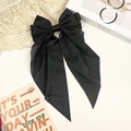 Close-up of a large black bow hairclip with long ribbons on an elegant vintage background - Black