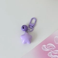Close-up of purple star keychain with bell and spring clasp on a clean white background - Purple