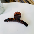 Close-up of amber brown resin hair claw clip with a sleek curved design on a white surface - Glossy Red Brown