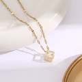 Gros plan du collier en titane doré avec pendentif cube évidé et zircon transparent - Collier diamant carré creux / Doré
