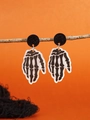 Detail of Halloween skeleton hand earrings hanging on a branch with orange background - WS10-3 (Skeleton Hand Design)