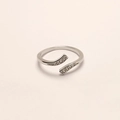 Detail van een verzilverde verstelbare ring met rijen zirkoon op een beige achtergrond - Verstelbaar Open / Verzilverde golvende zirkonia open stijl