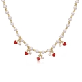 Detail of pearl bead necklace with red heart pendants and golden beads on white surface - Gold Pearl Red Cherry Necklace