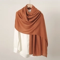 Detailed close-up of a caramel cotton linen scarf hanging on a wooden hanger with shirt - Orange Yellow