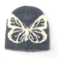 Detail van een donkergrijze gebreide muts met wit vlinderpatroon en pluche textuur - L(58-62cm) / Grijs