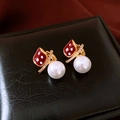 Dettaglio macro di orecchini placcati in oro con motivi rossi e perle bianche appese - Bianco-Rosso (Placcato Oro Vero)