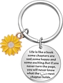 Macro detail of stainless steel sunflower keychain with engraved inspirational quote disk - Life is like a book