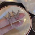 Silberne Schmetterlings-Ohrringe mit hohlen Flügeln und Perlen auf einer weißen Keramikplatte - Silber
