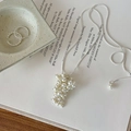Detail of silver snake chain necklace with white pearl grape cluster pendant on a table - Necklace-White